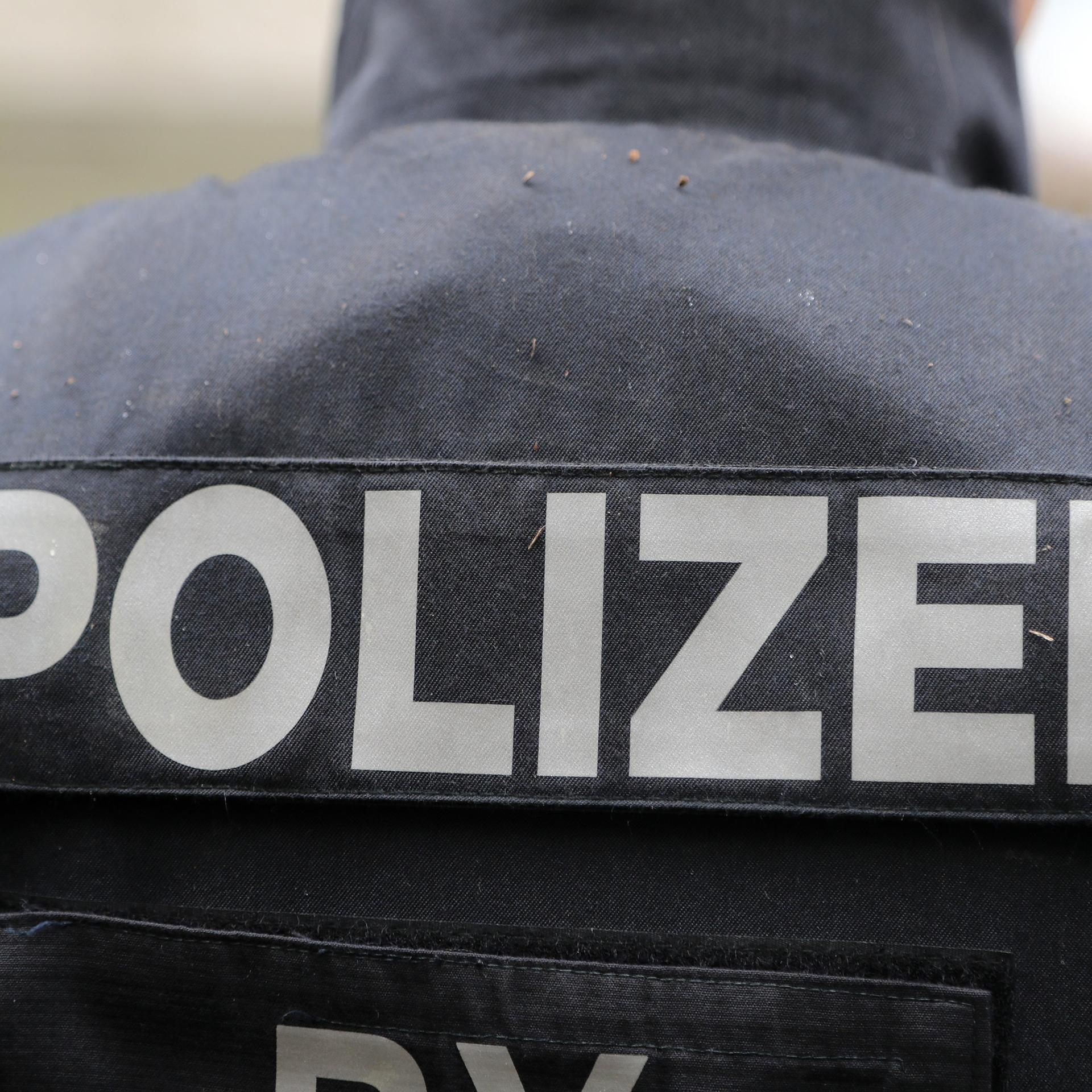 Blick auf den Schriftzug "Polizei" auf der Rückseite einer Weste eines Beamten als Symbolbild.