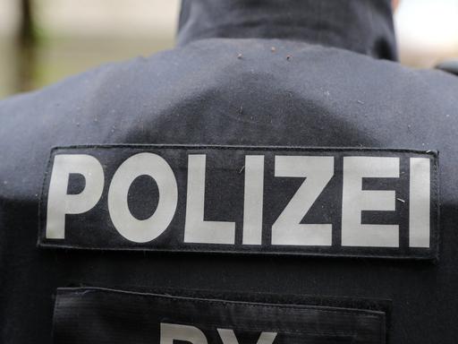 Blick auf den Schriftzug "Polizei" auf der Rückseite einer Weste eines Beamten als Symbolbild.