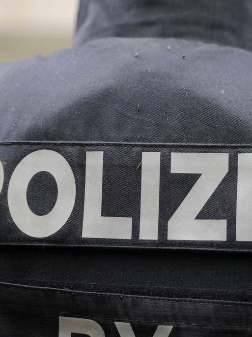 Blick auf den Schriftzug "Polizei" auf der Rückseite einer Weste eines Beamten als Symbolbild.