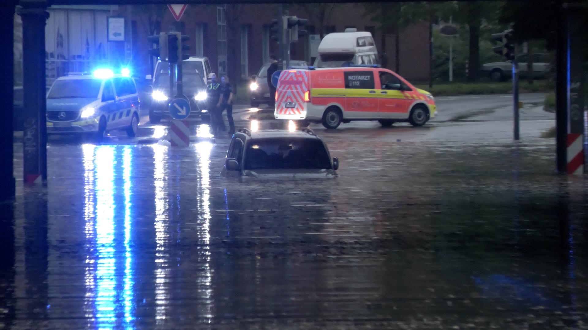 Ein Auto steht in einer überfluteten Straße in einer Unterführung. Ein Auto steht in einer überfluteten Straße in einer Unterführung.
