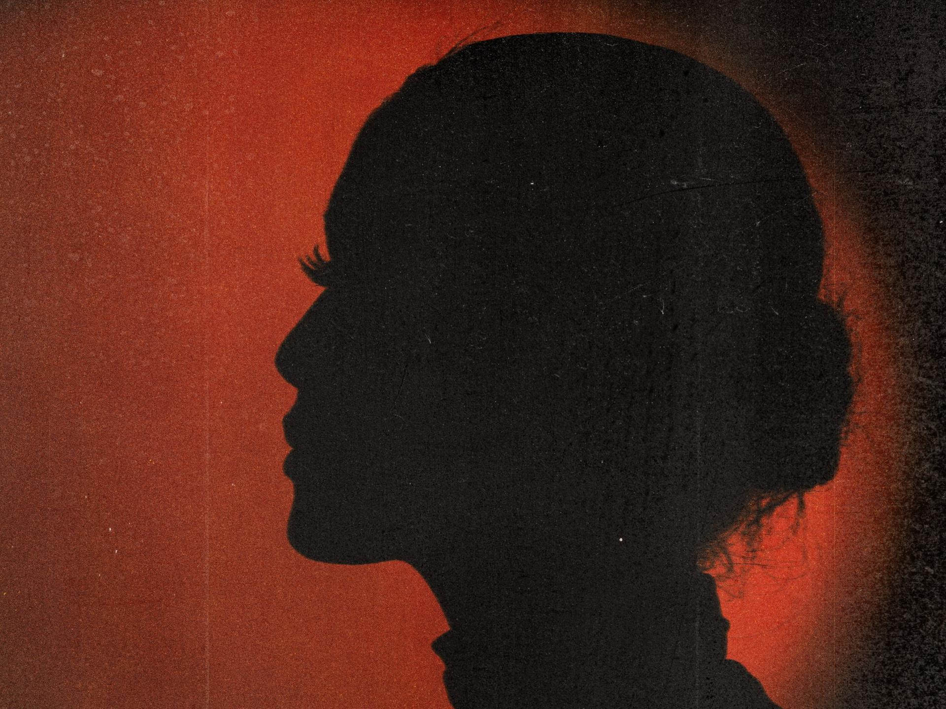 Die Silhoette einer Frau im Profil hebt sich schwarz vor einem roten Hintergrund ab.