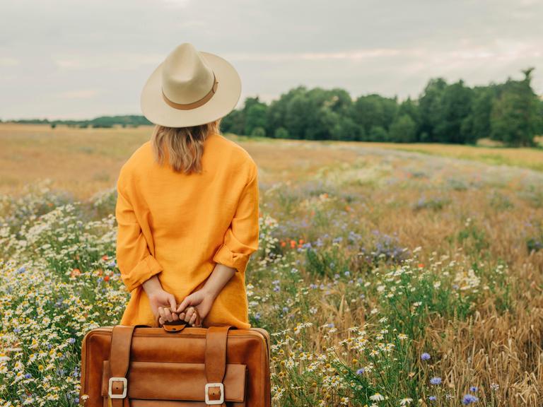 Woman standing with briefcase at chamomile field || Modellfreigabe vorhanden