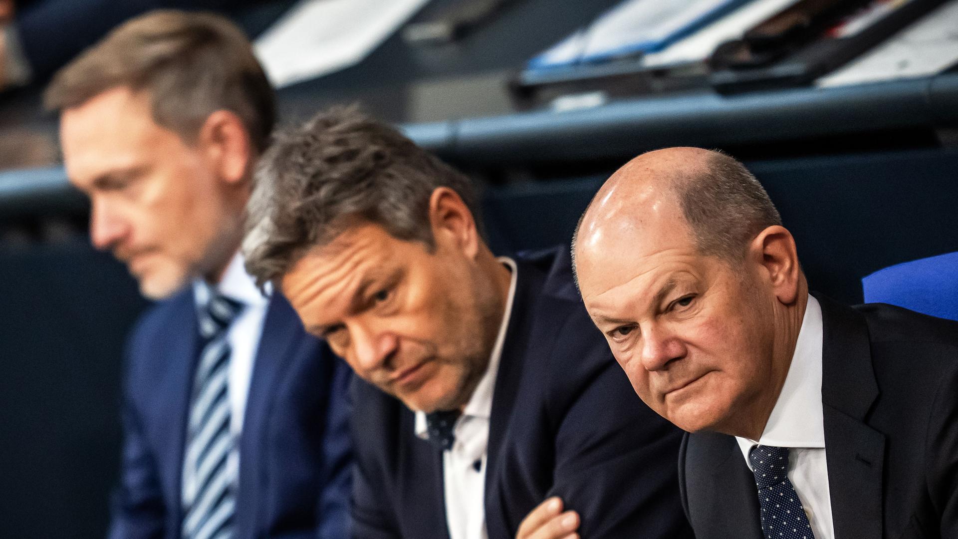 Bundeskanzler Olaf Scholz (SPD, r), verfolgt neben Robert Habeck (Bündnis 90/Die Grünen, M), Bundesminister für Wirtschaft und Klimaschutz, und Christian Lindner (FDP), Bundesminister der Finanzen, die Debatte nach einer Regierungserklärung zur Haushaltslage im Bundestag.