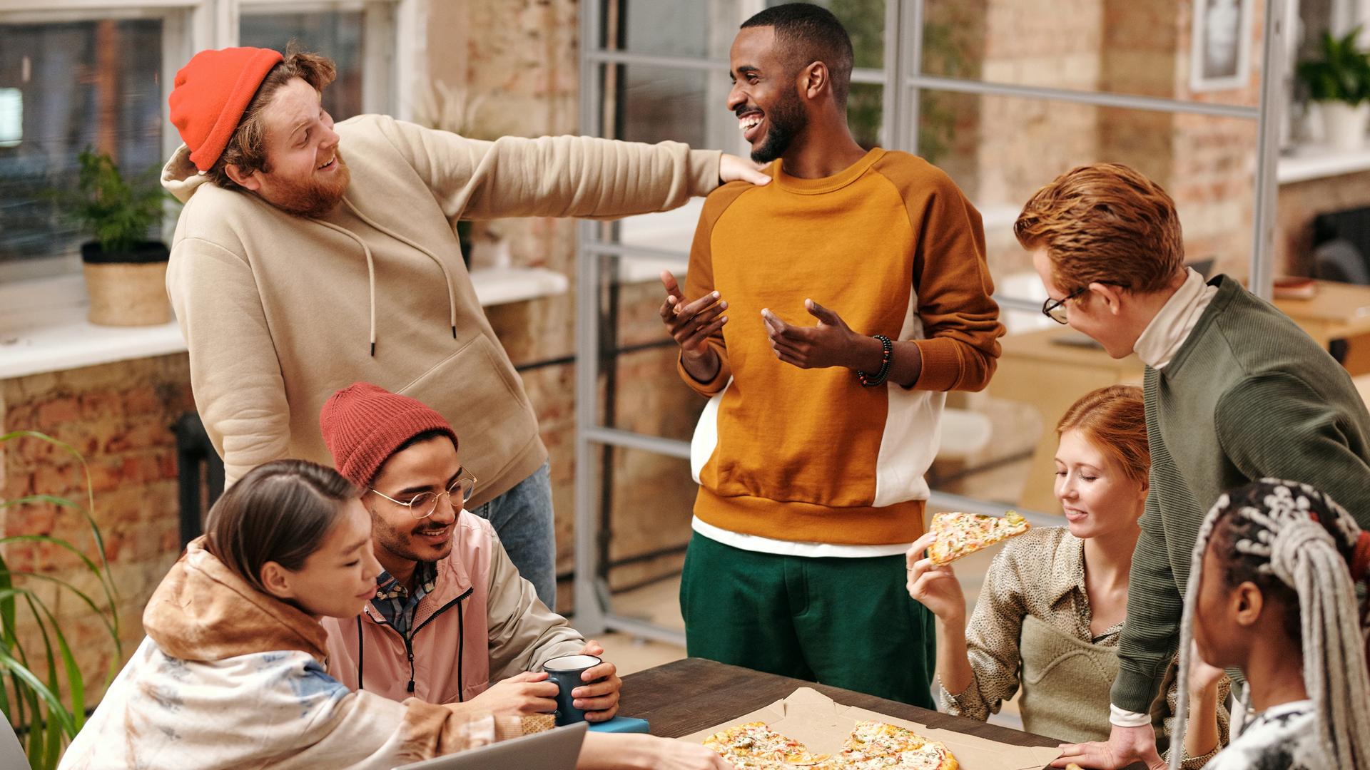 Eine Gruppe junger Menschen isst zusammen Pizza und unterhält sich