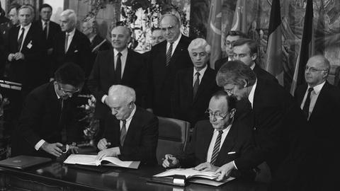  Michail Gorbatschow., Bundesaußenminister Hans-Dietrich Genscher und Außenminister Eduard Schewardnadse unterzeichnen den Vertrag zur Deutschen Einheit in Moskau, dahinter Bundeskanzler Helmut Kohl und Präsident Michail Gorbatschow