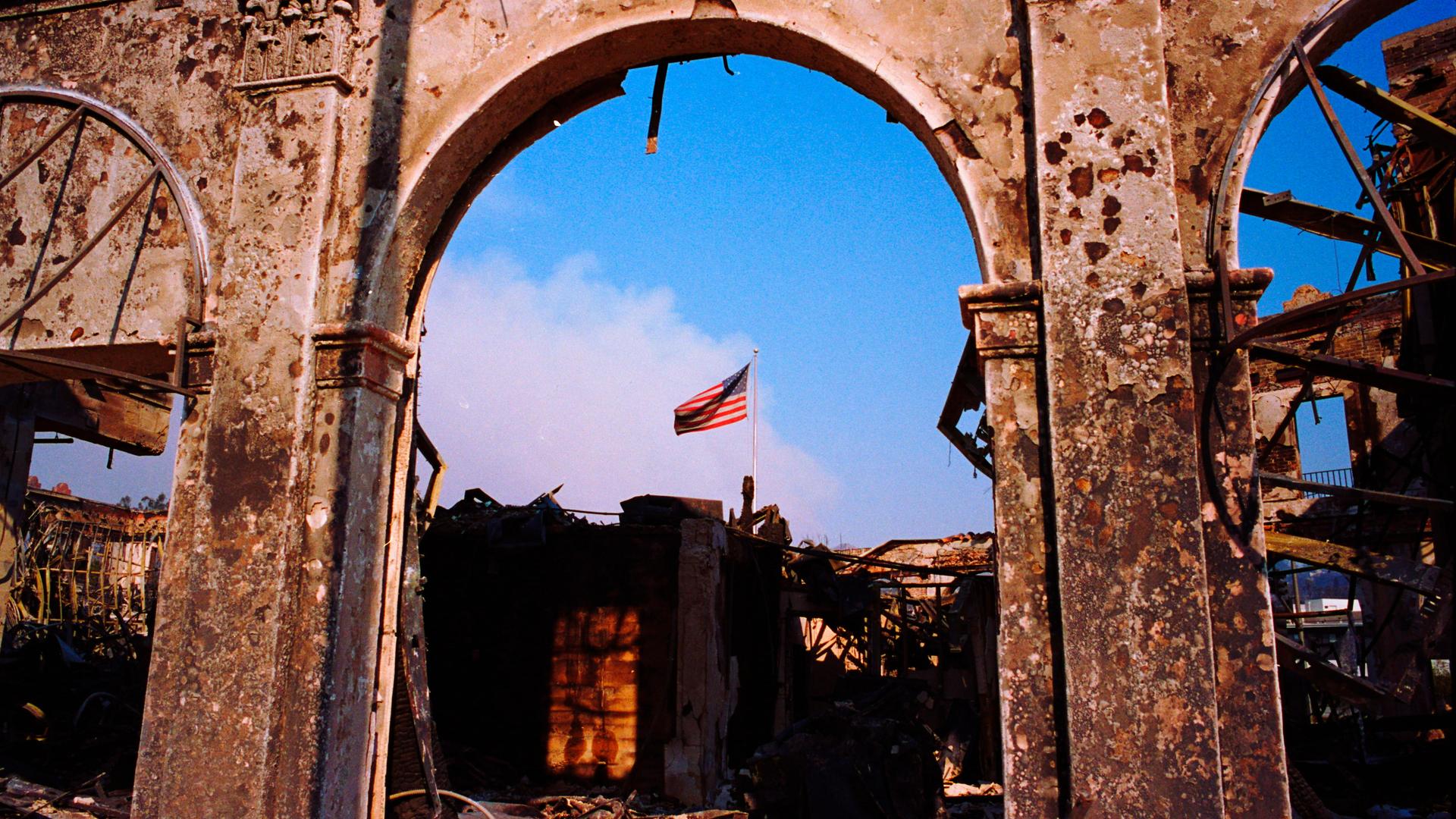 Ein Blick auf ein vom Feuer zerstörtes Gebäude gibt den Blick auf die amerikanische Flagge frei.