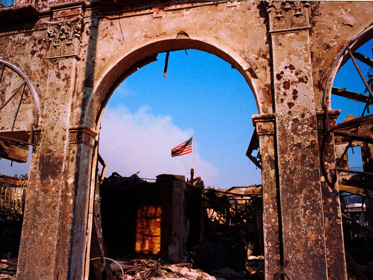 Ein Blick auf ein vom Feuer zerstörtes Gebäude gibt den Blick auf die amerikanische Flagge frei.