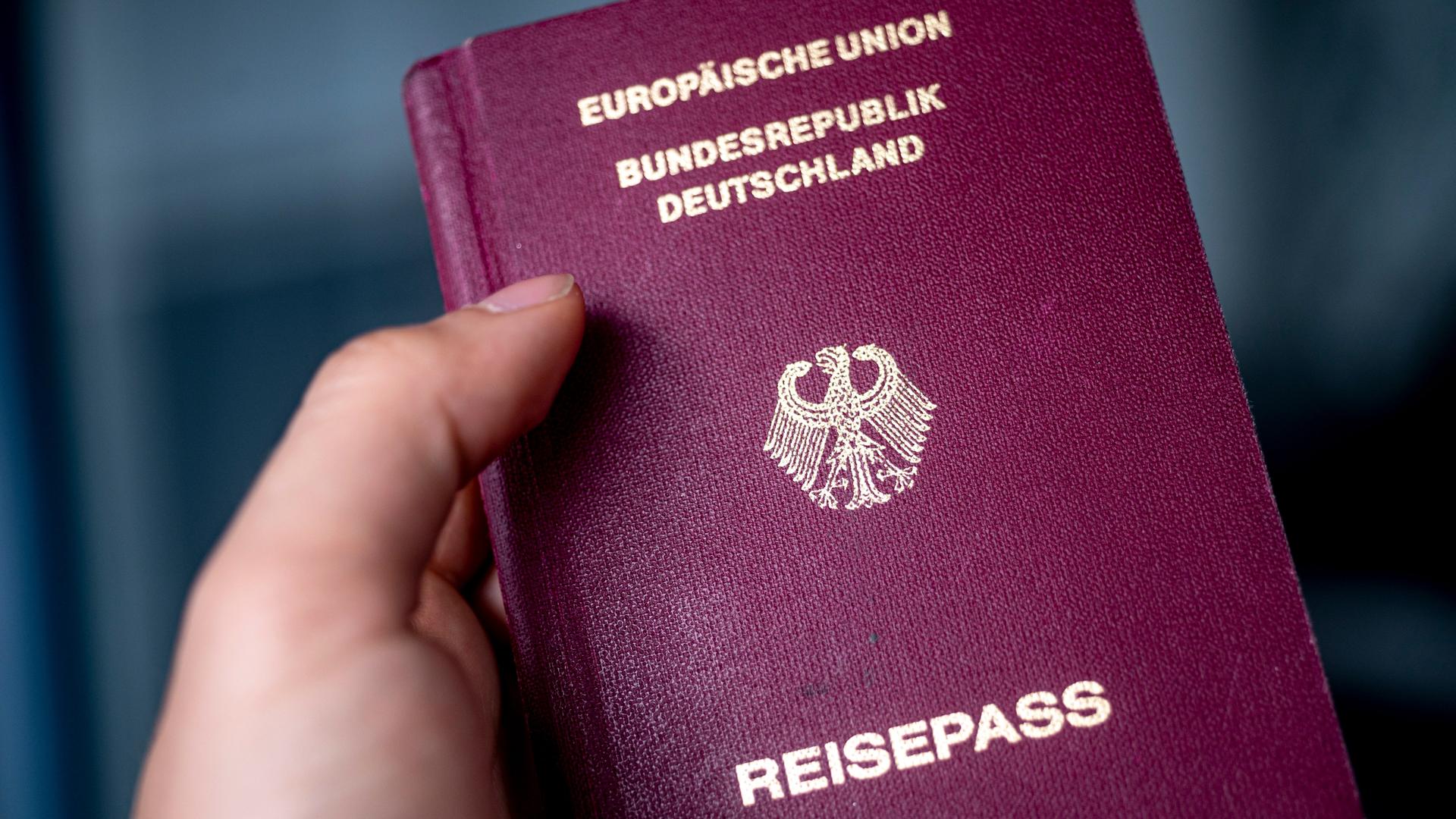 Eine Hand hält einen Pass. Einen dunkelrot eingebundenen Pass mit folgender Prägung in goldenen Buchstaben: Europäische Union. Bundesrepublik Deutschland. 