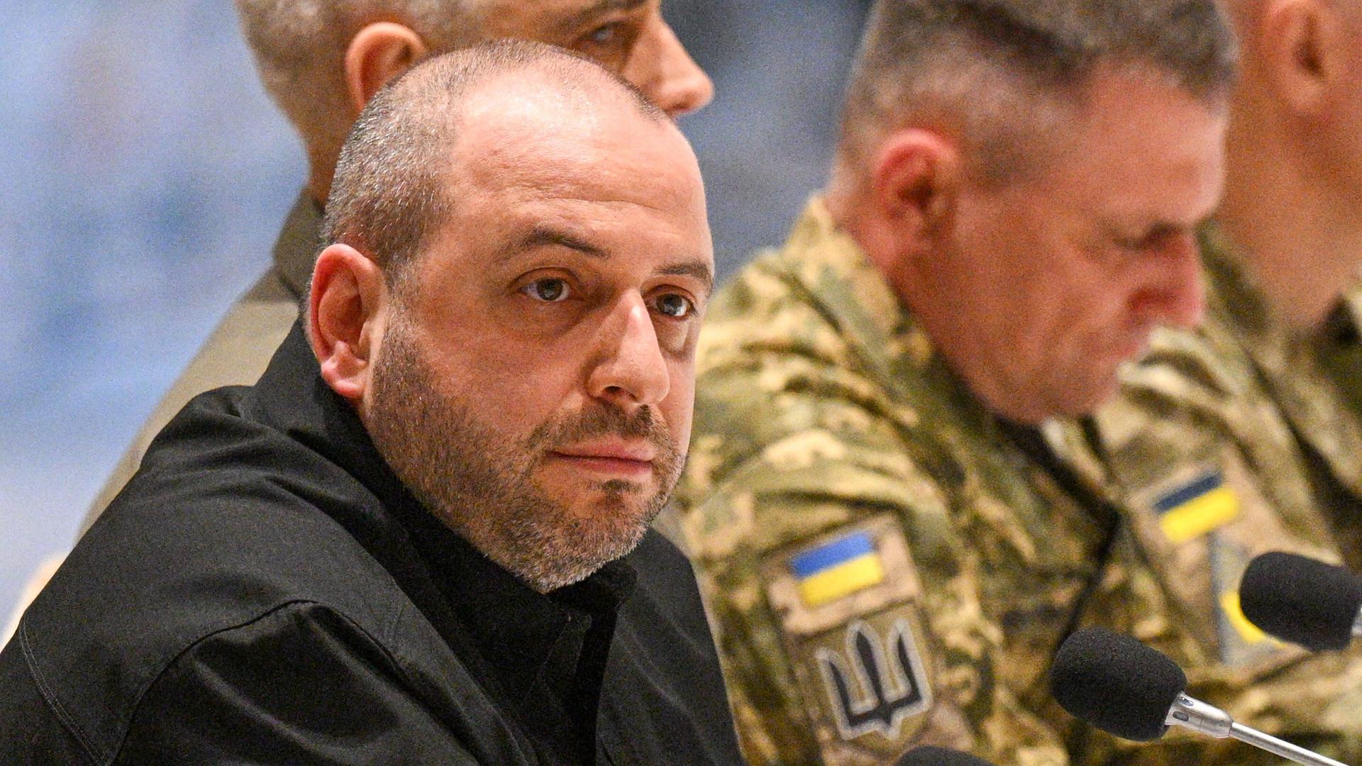 Das Bild zeigt den Leiter der ukrainischen Delegation, Verteidigungsminister Rustem Umerov, sitzend im schwarzen Oberteil. Im Hintergrund sitzen ukrainische Militärangehörige in Tarnanzügen. 