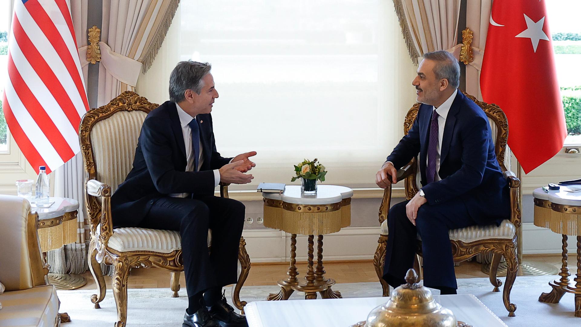US-Außenminister Blinken und der türkische Außenminister Fidan sitzen auf Stühlen und sprechen miteinander.