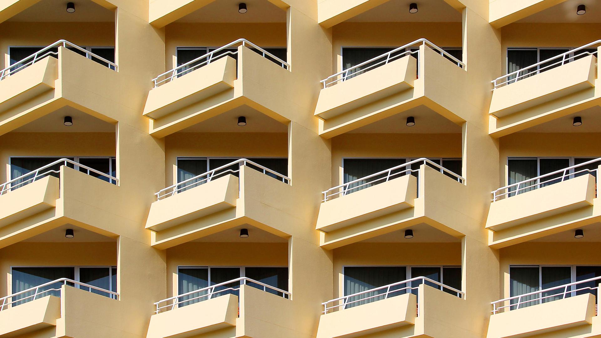Blick auf ein mehrstöckiges Wohnhaus mit gelber Fassade und vielen Balkonen