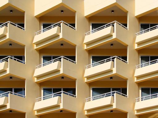 Blick auf ein mehrstöckiges Wohnhaus mit gelber Fassade und vielen Balkonen