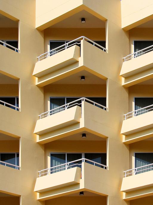 Blick auf ein mehrstöckiges Wohnhaus mit gelber Fassade und vielen Balkonen
