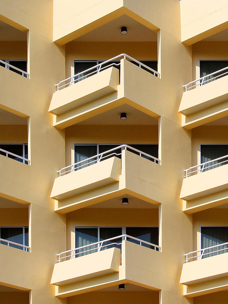 Blick auf ein mehrstöckiges Wohnhaus mit gelber Fassade und vielen Balkonen