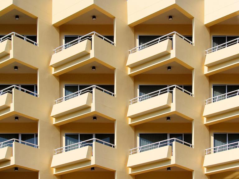 Blick auf ein mehrstöckiges Wohnhaus mit gelber Fassade und vielen Balkonen