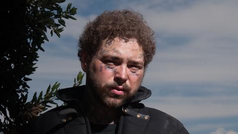 Post Malone, Rapper mit tätowiertem Gesicht, schaut in die Kamera