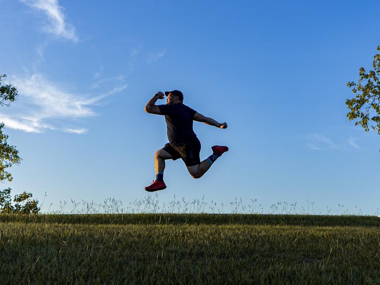 Ein Mann, der in der Landschaft in die Luft hüpft. Ein Mann, der in der Landschaft in die Luft hüpft.