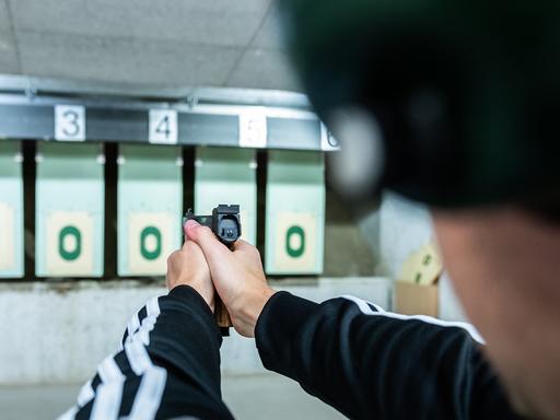 Ein Mann zielt während eines Schießtrainings am Schießstand mit einer Pistole auf eine Zielscheibe.