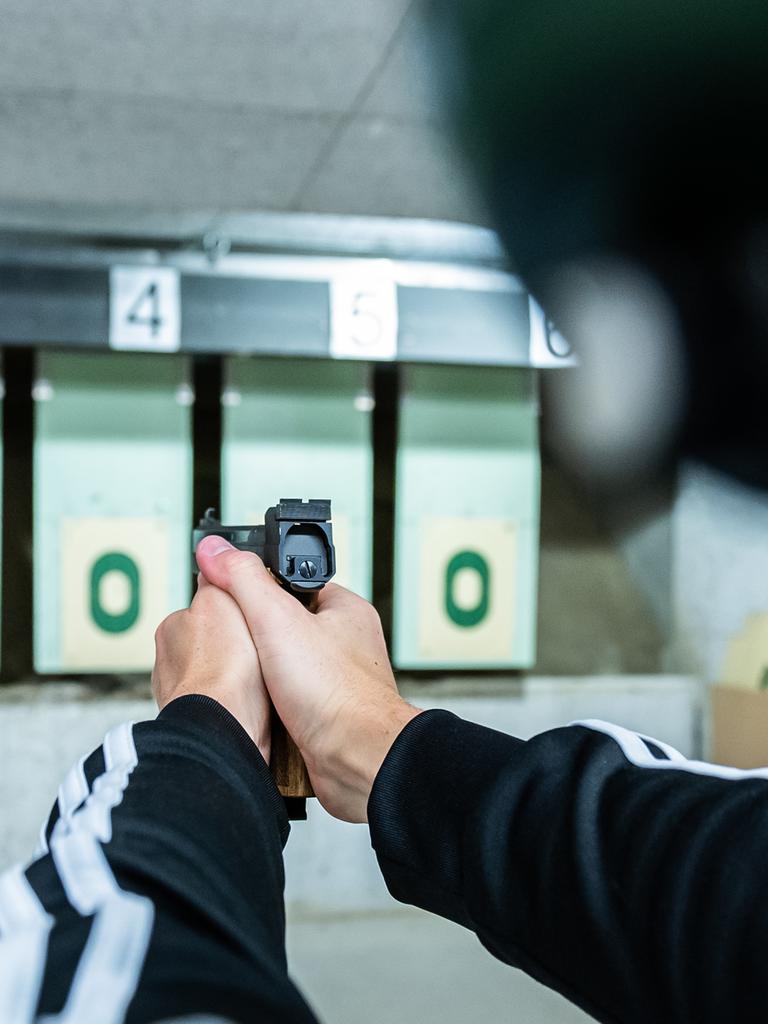 Ein Mann zielt während eines Schießtrainings am Schießstand mit einer Pistole auf eine Zielscheibe.