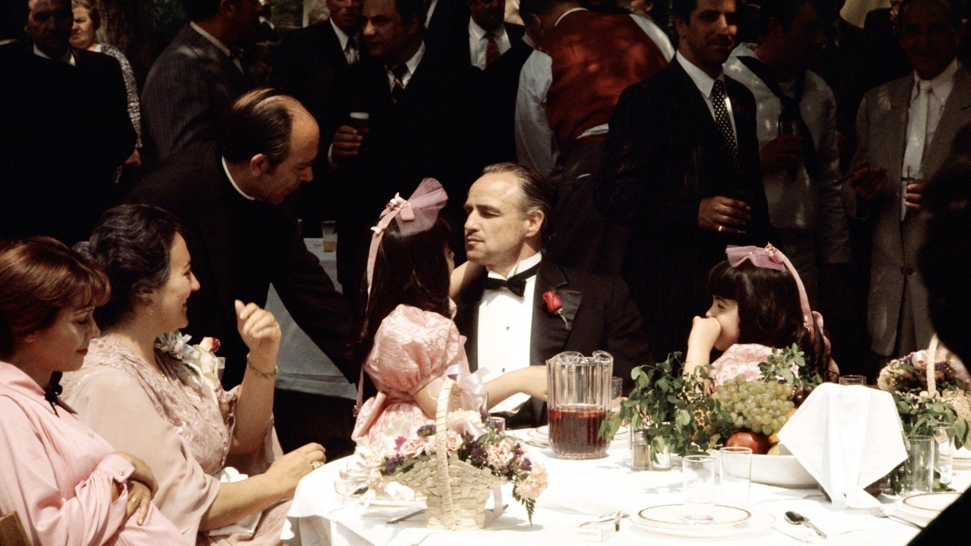 Der Schauspieler Marlon Brando sitzt in dem Film "Der Pate" an einem Tisch und ist von Frauen und Untergebenen umringt. Der Schauspieler Marlon Brando sitzt in dem Film "Der Pate" an einem Tisch und ist von Frauen und Untergebenen umringt.