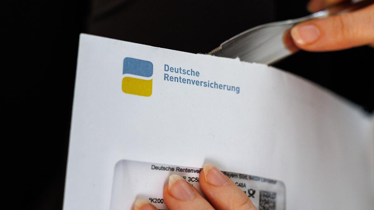 Eine Frau öffnet einen Briefumschlag, auf dem das Logo und der Schriftzug der deutschen Rentenversicherung zu sehen ist.