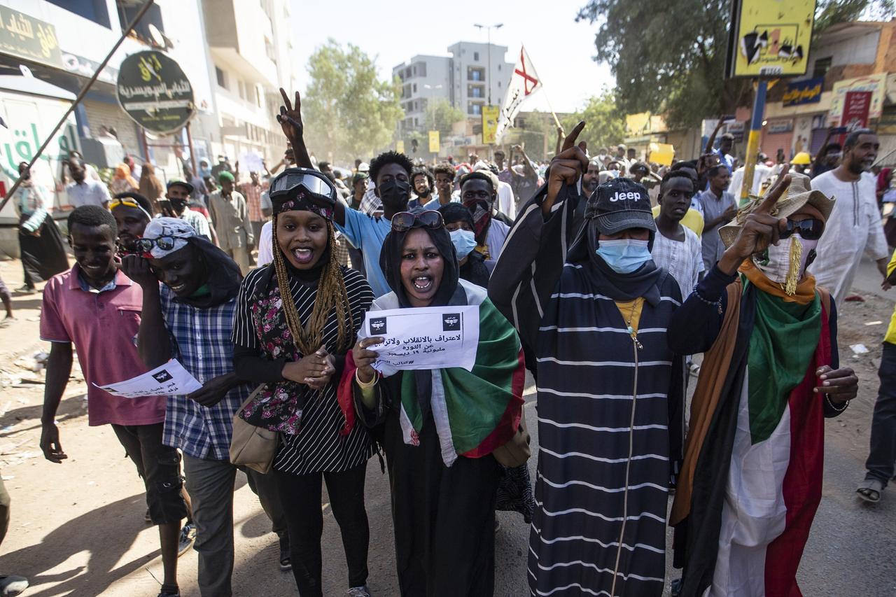 Demonstrant*innen gehen mit Plakaten durch Khartoum, Sudan. 