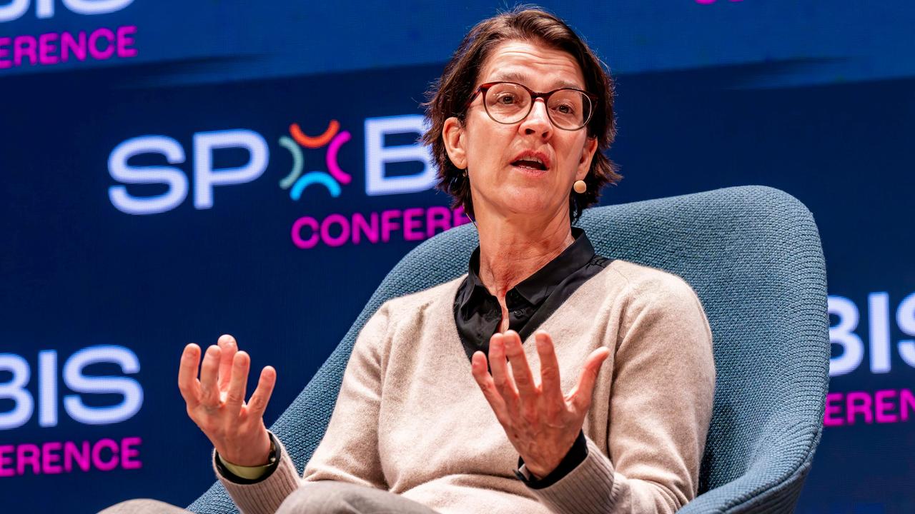 Haenni sitzt in einem Sessel und gestikuliert mit beiden Händen. Dahinter eine dunkle Wand mit weiß-lila Logos der Spobis-Sportkonferenz.