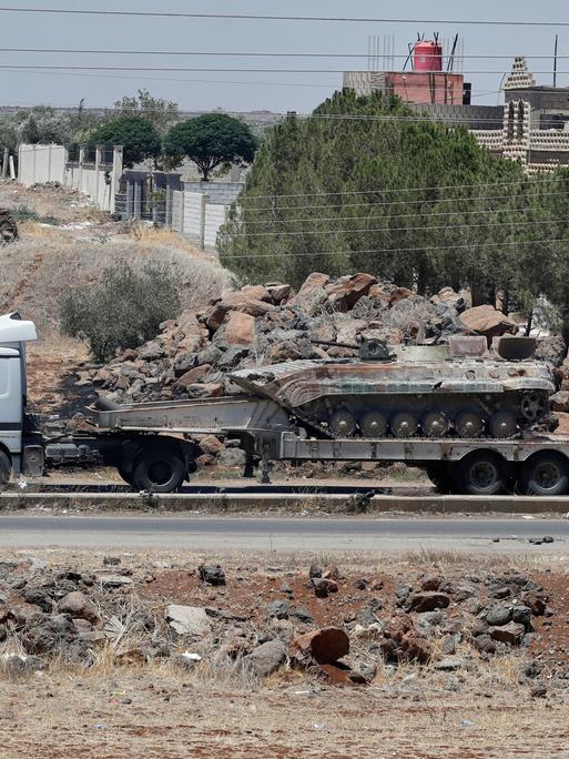 Ein auf einem Lastwagen transportierter Panzer der syrischen Regierungstruppen, die sich aus der Stadt Suweida zurückziehen, passiert das Dorf Mazraa. 