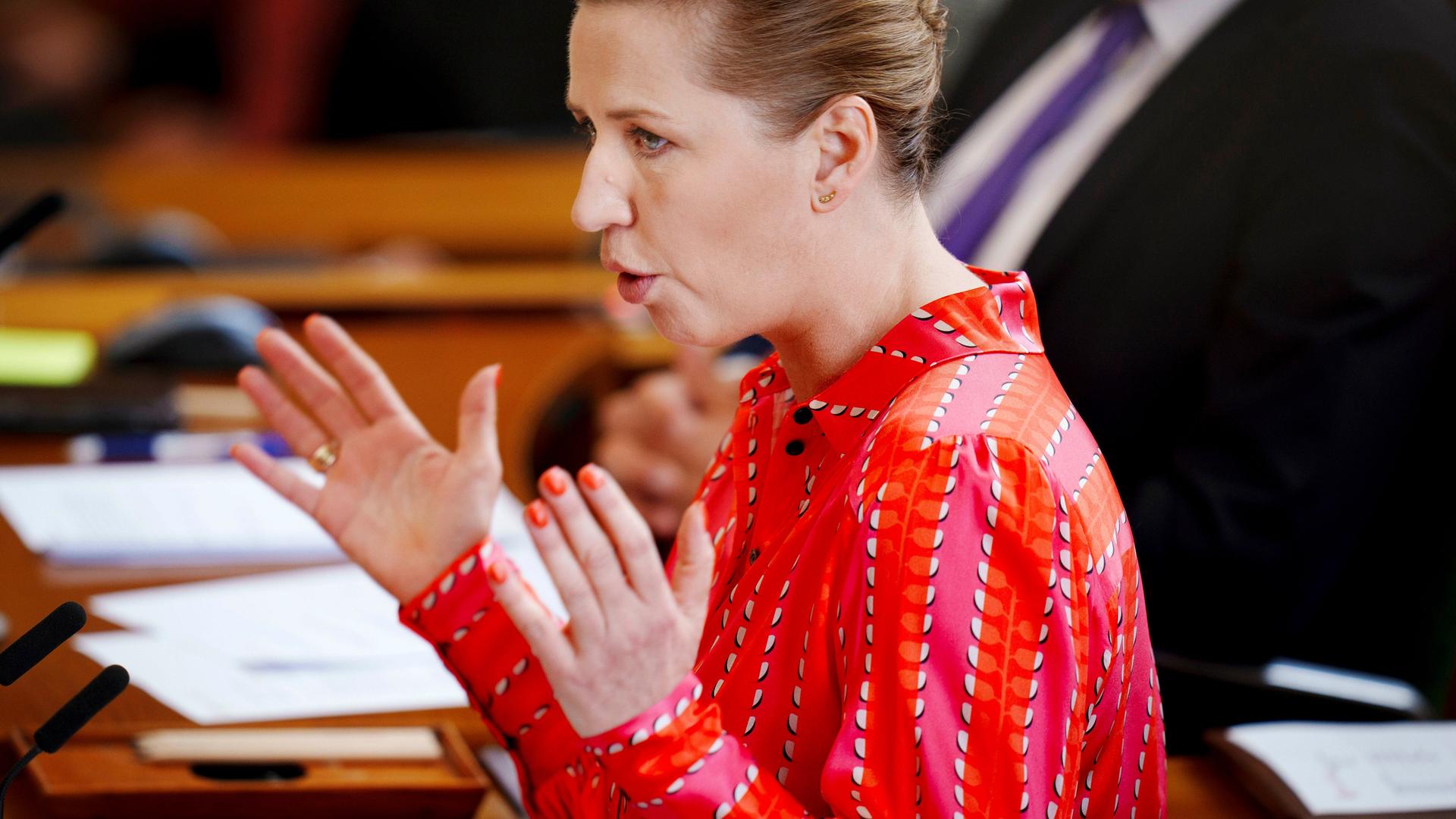 Dänemarks Ministerpräsidentin Mette Frederiksen hält eine Rede. Sie hat beide Hände gehoben.