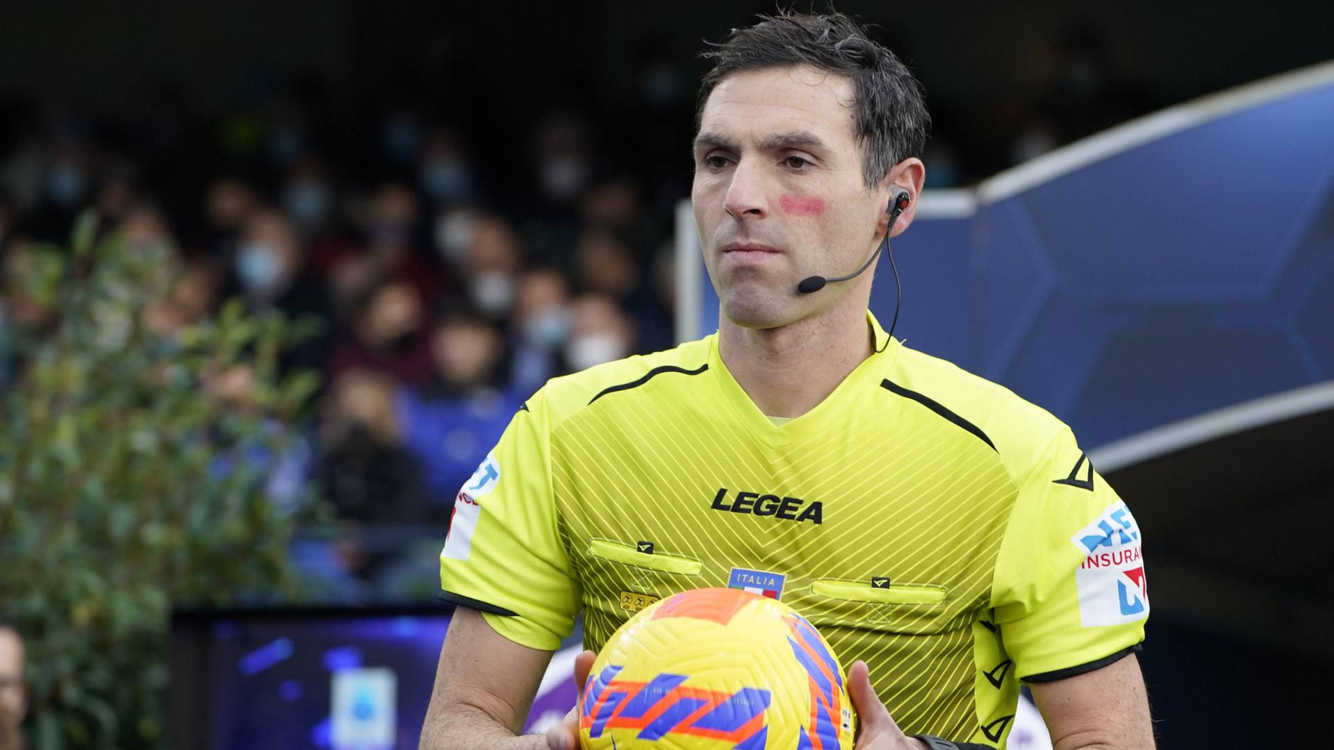 Ein Schiedsrichter hält einen Fußball in den Händen, im Gesicht hat er eine rote Markierung unter dem linken Auge. Ein Schiedsrichter hält einen Fußball in den Händen, im Gesicht hat er eine rote Markierung unter dem linken Auge.