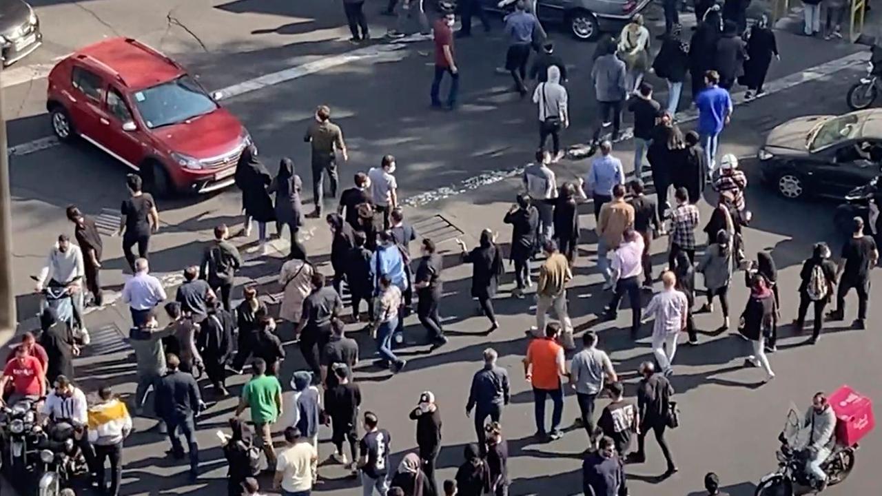 Iran, Teheran: Menschen blockieren während einer Demonstration eine Kreuzung.