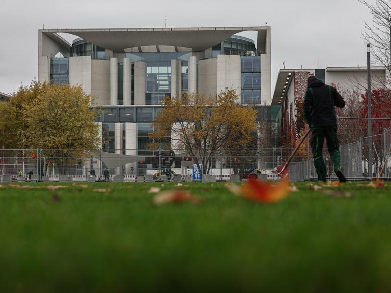 Ein Mensch recht Laub vor dem Kanzleramt. Am Mittwochabend entließ der Bundeskanzler den Finanzminister und kündige Neuwahlen für das kommende Frühjahr an.