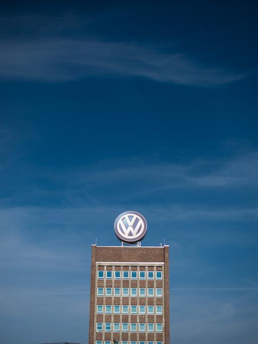 Blauer Himmel über dem Verwaltungshochhaus am Volkswagen-Werk in Wolfsburg, auf dem ein großes VW-Logo angebracht ist.