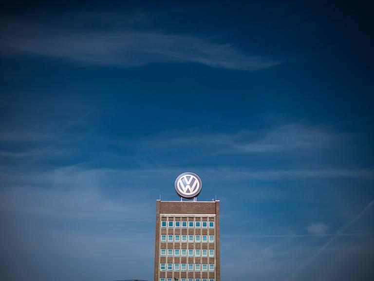 Blauer Himmel über dem Verwaltungshochhaus am Volkswagen-Werk in Wolfsburg, auf dem ein großes VW-Logo angebracht ist.