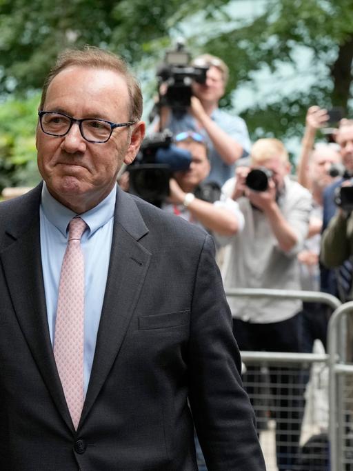 Kevin Spacey verlässt den Southwark Crown Court und lächelt. Im Hintergrund stehen viele Fotografen.