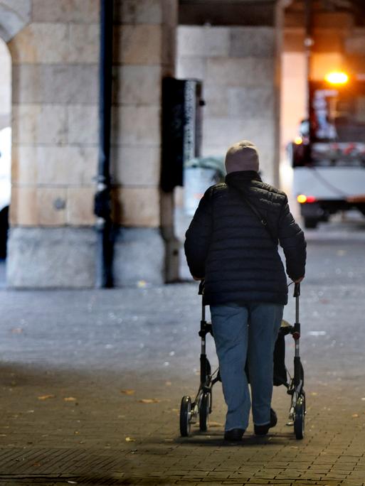 Rentnerpaar mit Rolator und Einkaufswagen in einer Unterführung im Halbdunkeln 