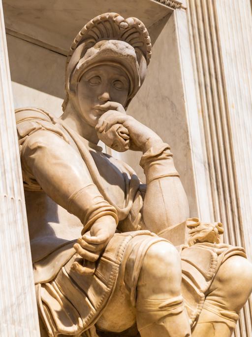 Blick auf eine Figur Michelangelos an der Kapelle Medici in Florenz, die nachdenklich ihren Kopf in die Hand stützt.