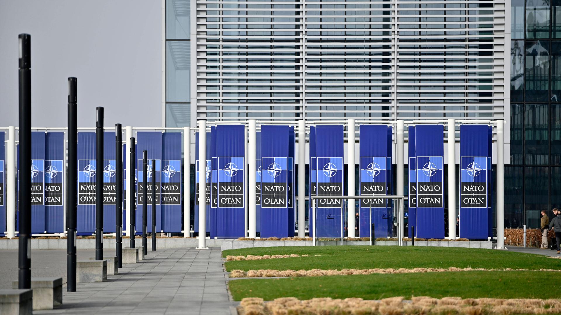 Das NATO-Hauptquartier in Brüssel von aussen, mit NATO-Logos vor der Tür.