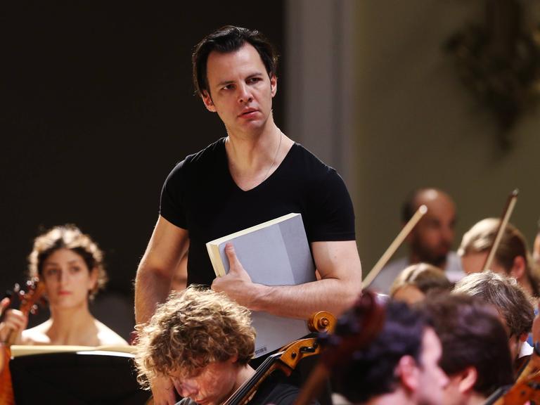Dirigent Teodor Currentzis inmitten von Orchestermitgliedern seines Ensembles MusicAeterna bei einer Probe.