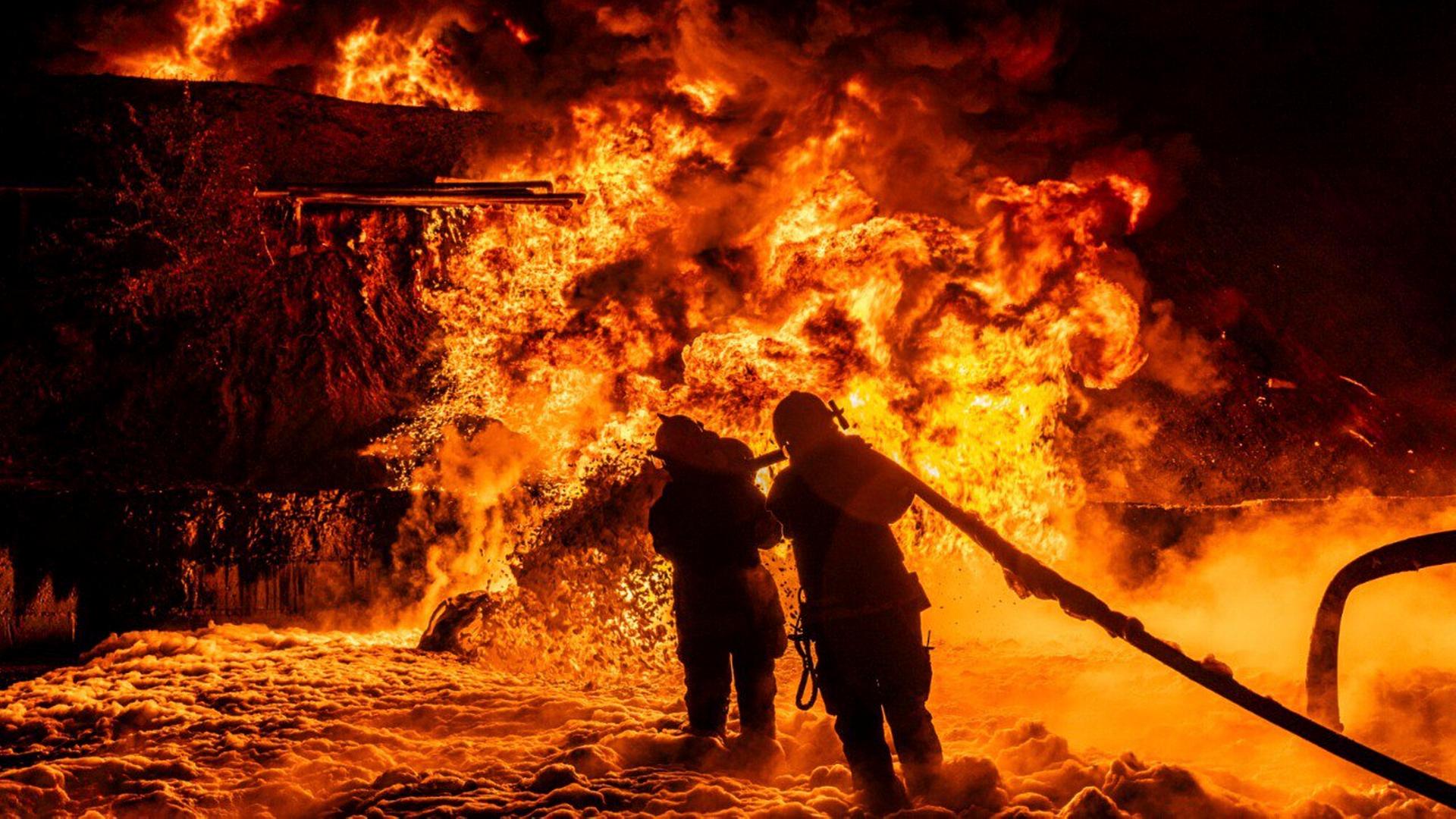 Feuerwehrleuten kämpfen nach einem Angriff auf Charkiw gegen die Flammen.