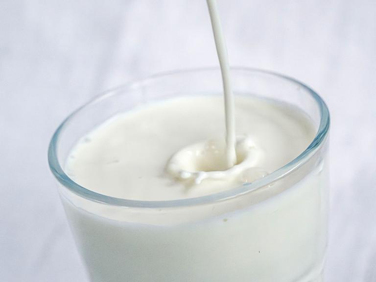 Milch wird in ein Glas gefüllt