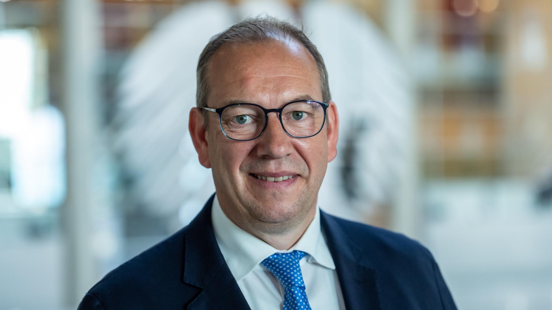 Henning Otte (CDU), aufgenommen nach seiner Wahl als neuer Wehrbeauftragter des Bundestags. Er lächelt verhalten. Im Hintergrund ist unscharf der Bundesadler auf einer Glasscheibe zu erkennen. 