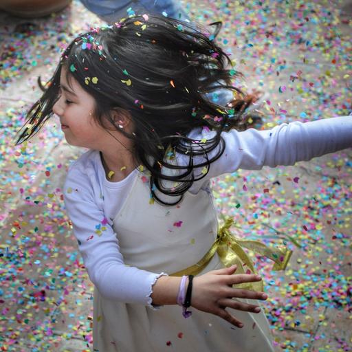 Ein Kind wirbelt im Konfettiregen um die eigene Achse.