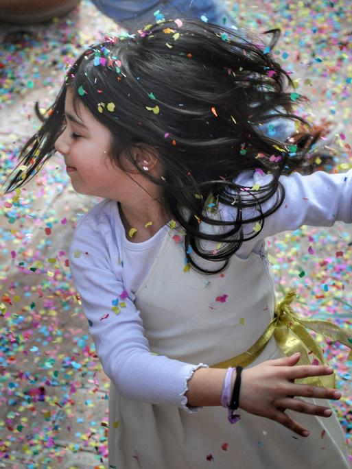 Ein Kind wirbelt im Konfettiregen um die eigene Achse.