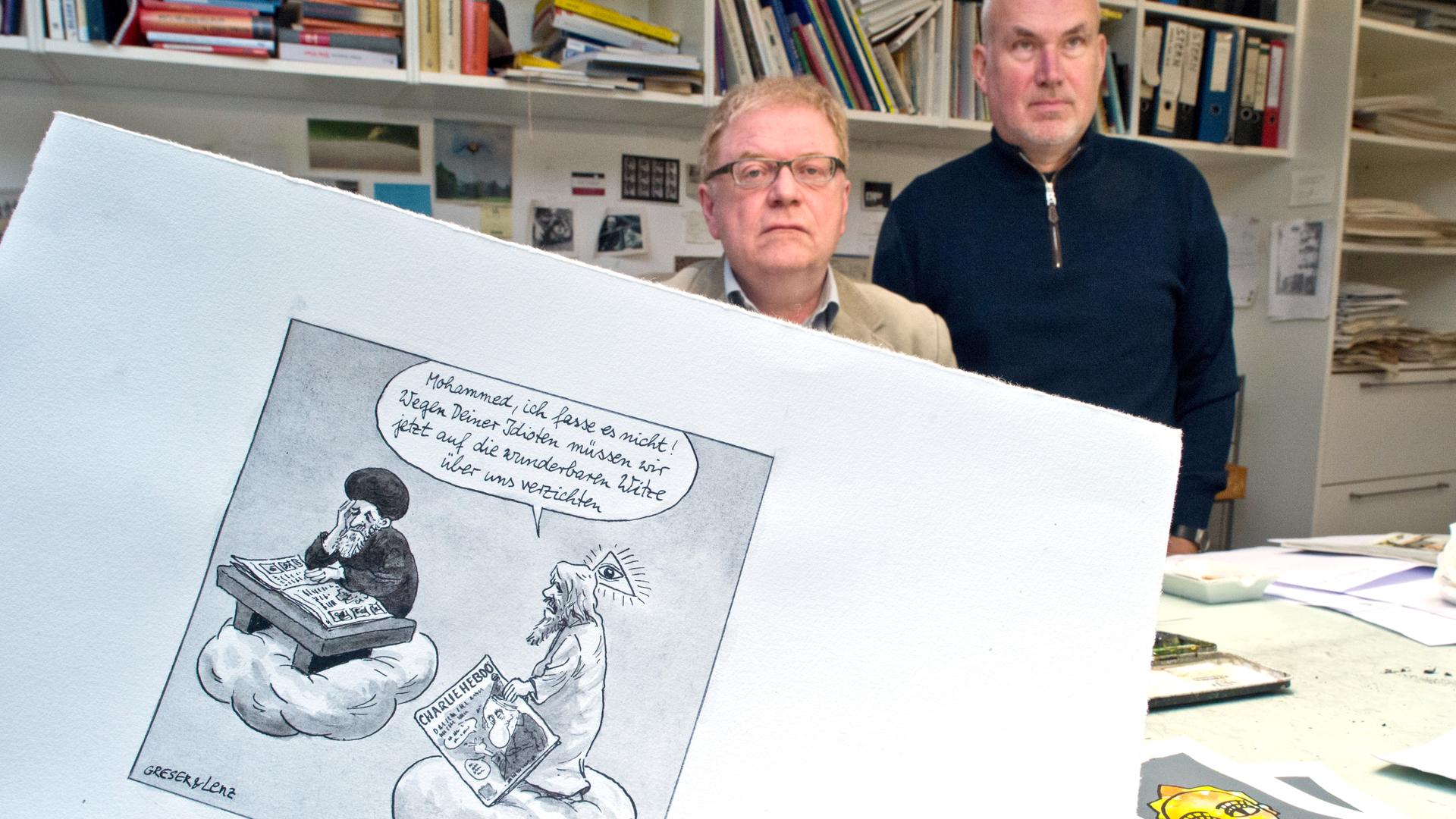 Die beiden Karikaturisten Achim Greser (l) und Heribert Lenz hier 2015 in ihrem Atelier mit einer ihrer Mohamed Karikaturen nach den Anschlägen gegen die Redaktion von "Charlie Hebdo"