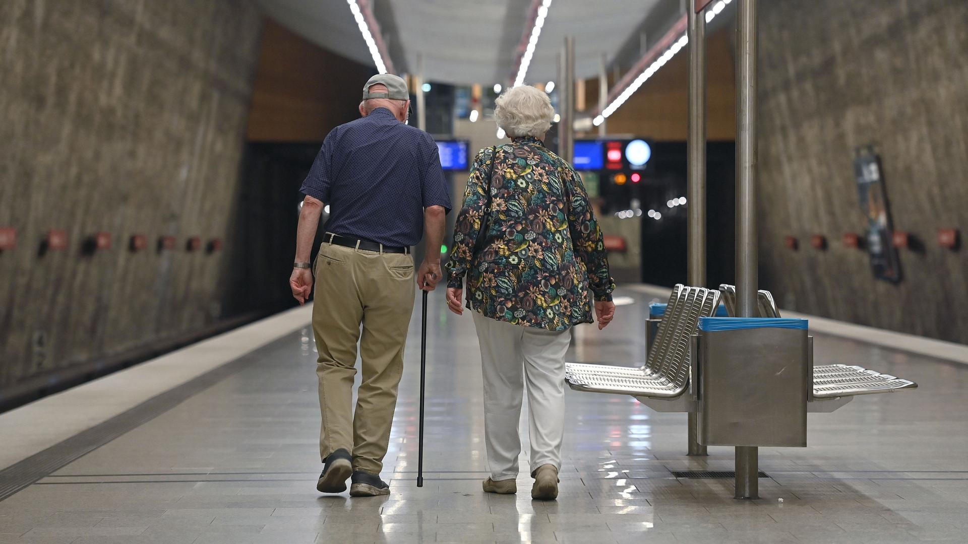 Ein älteres Paar geht über einen leeren U-Bahn-Bahnsteig.