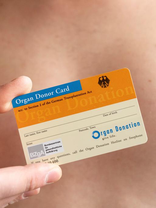 Ein Mann mit freiem Oberkörper hält einen Organspendeausweis in der Hand. Ein Mann mit freiem Oberkörper hält einen Organspendeausweis in der Hand.