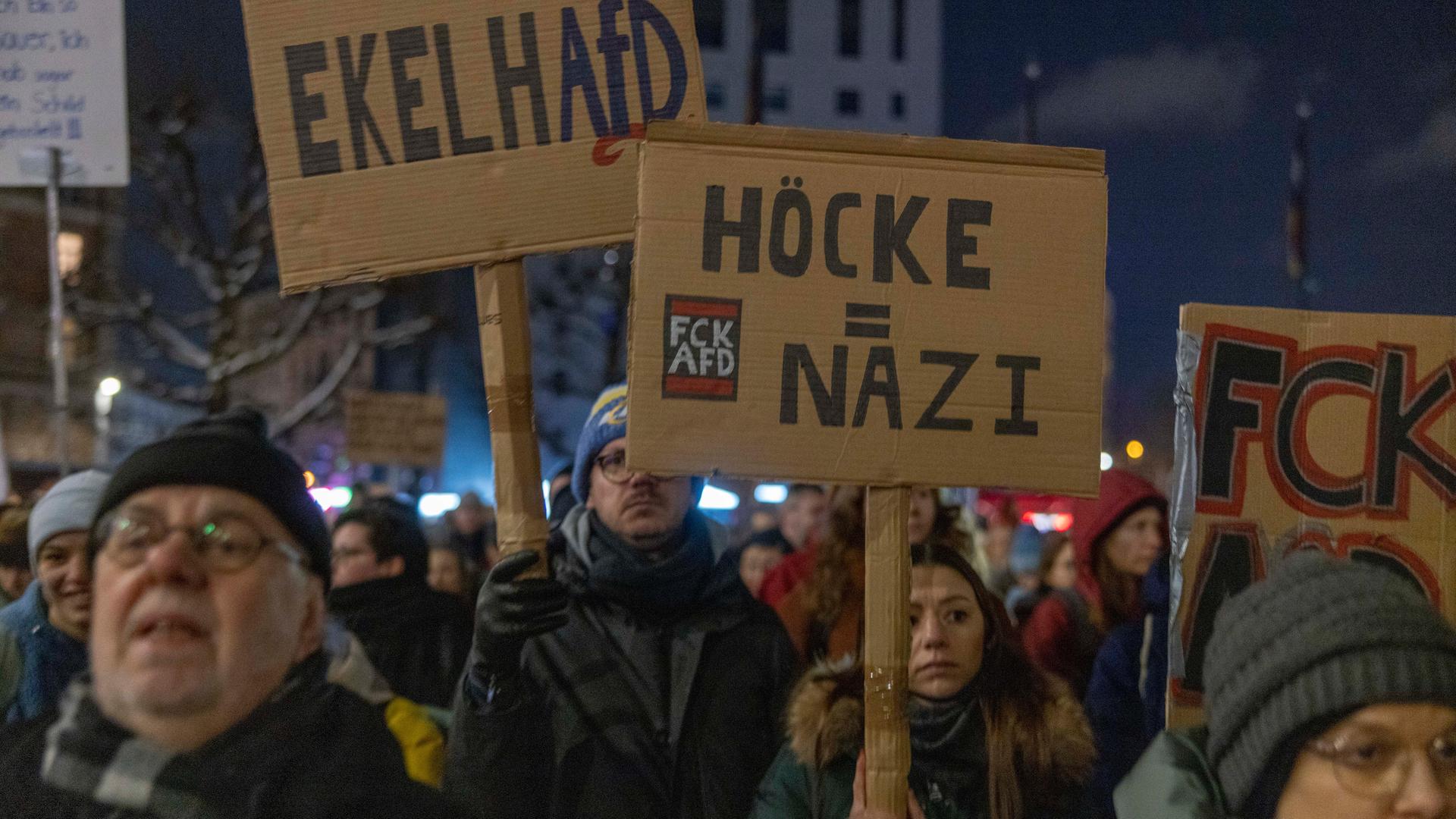 In der nächtlichen Mainzer Innenstadt halten Menschen Plakate mit Aufschriften wie "EkelhAfD" und "Höcke=Nazi" in die Höhe.