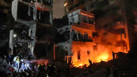 Menschen versammeln sich in Beirut vor zerstörten Gebäuden, die von einem Luftangriff getroffen wurden.