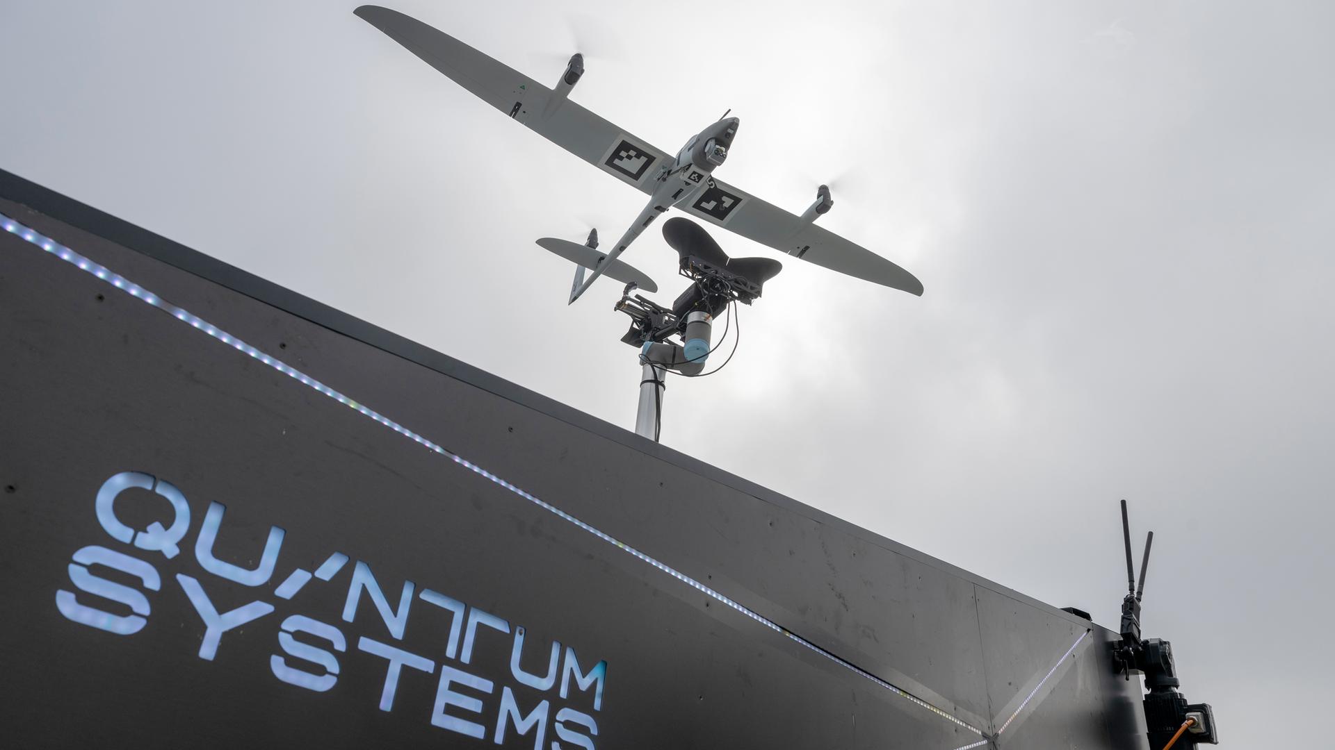 Die Aufklährungsdrohne "Vector AI" in der Luft, darunter ein Gebäude mit dem Schriftzug "Quantum Systems".